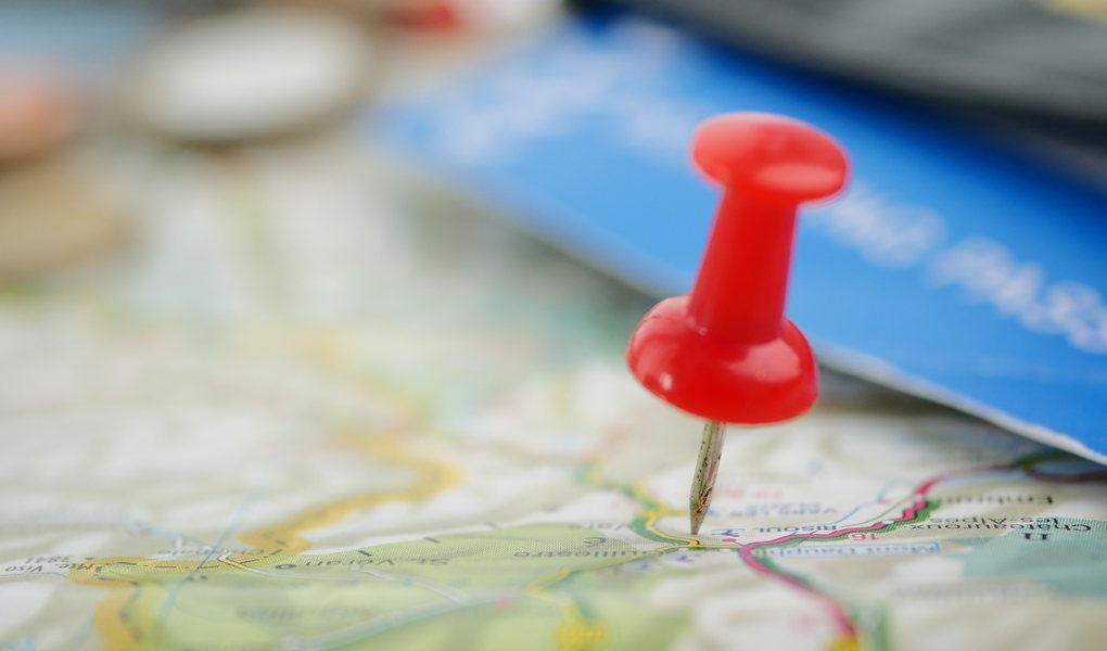 A red pin pushed into a road map