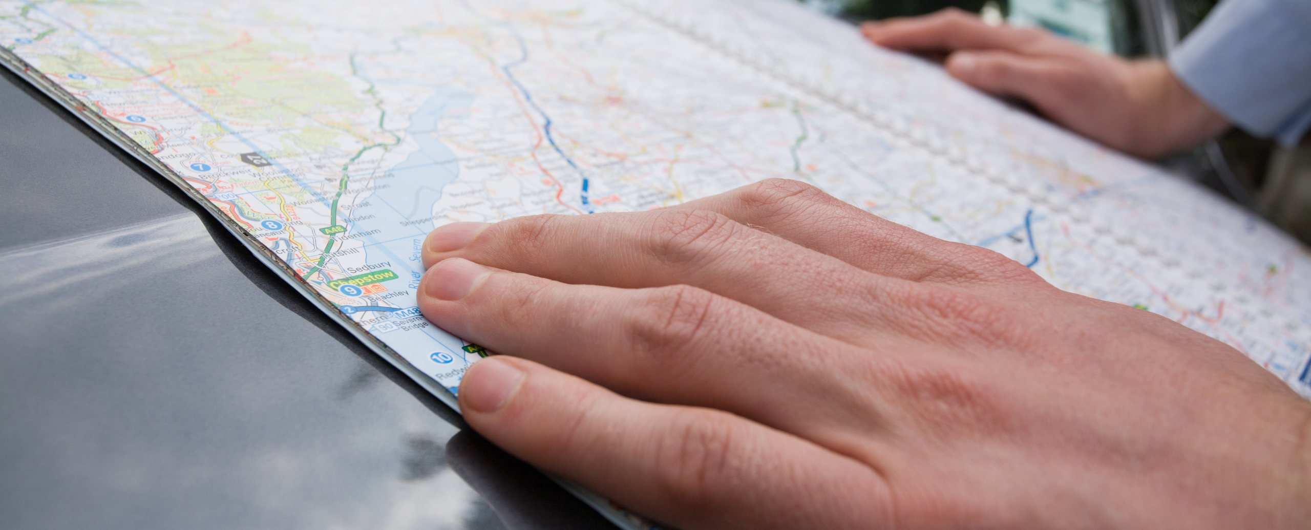 A hand resting on an open road map, marking a location