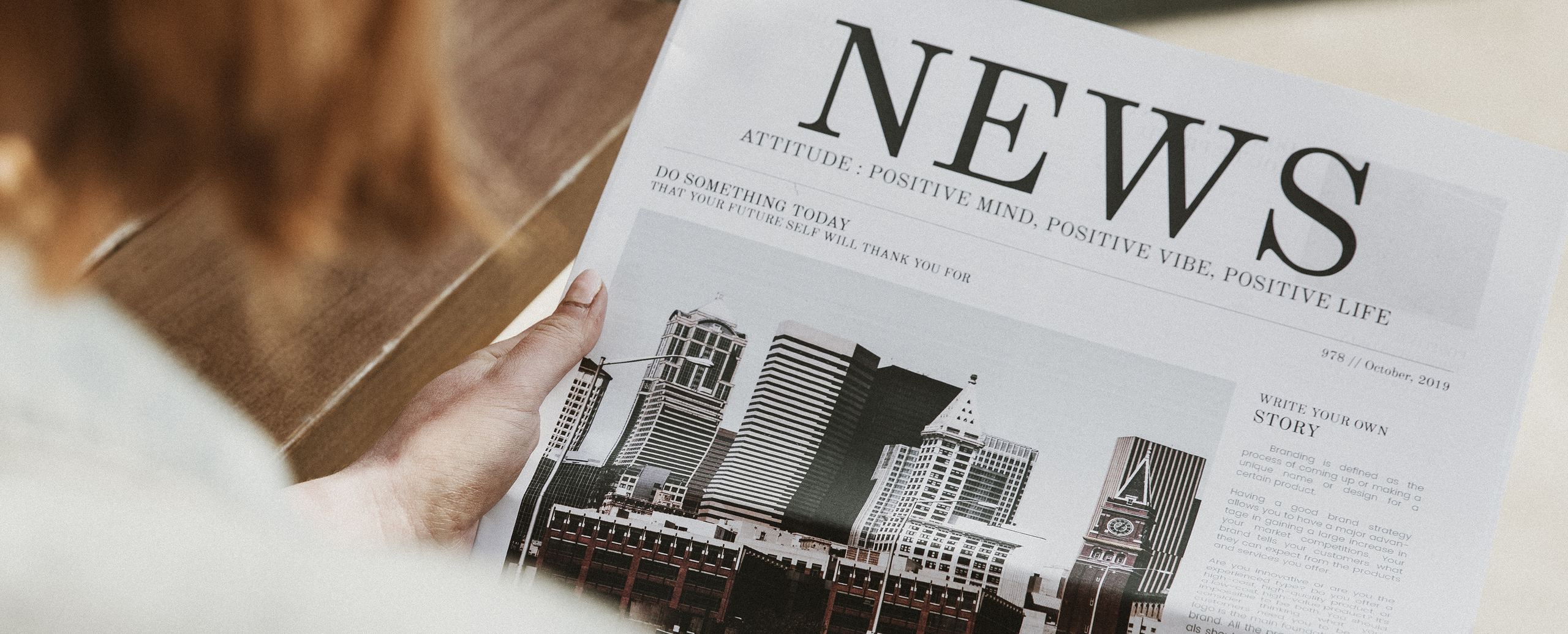 An over-the-shoulder view of someone reading a newspaper