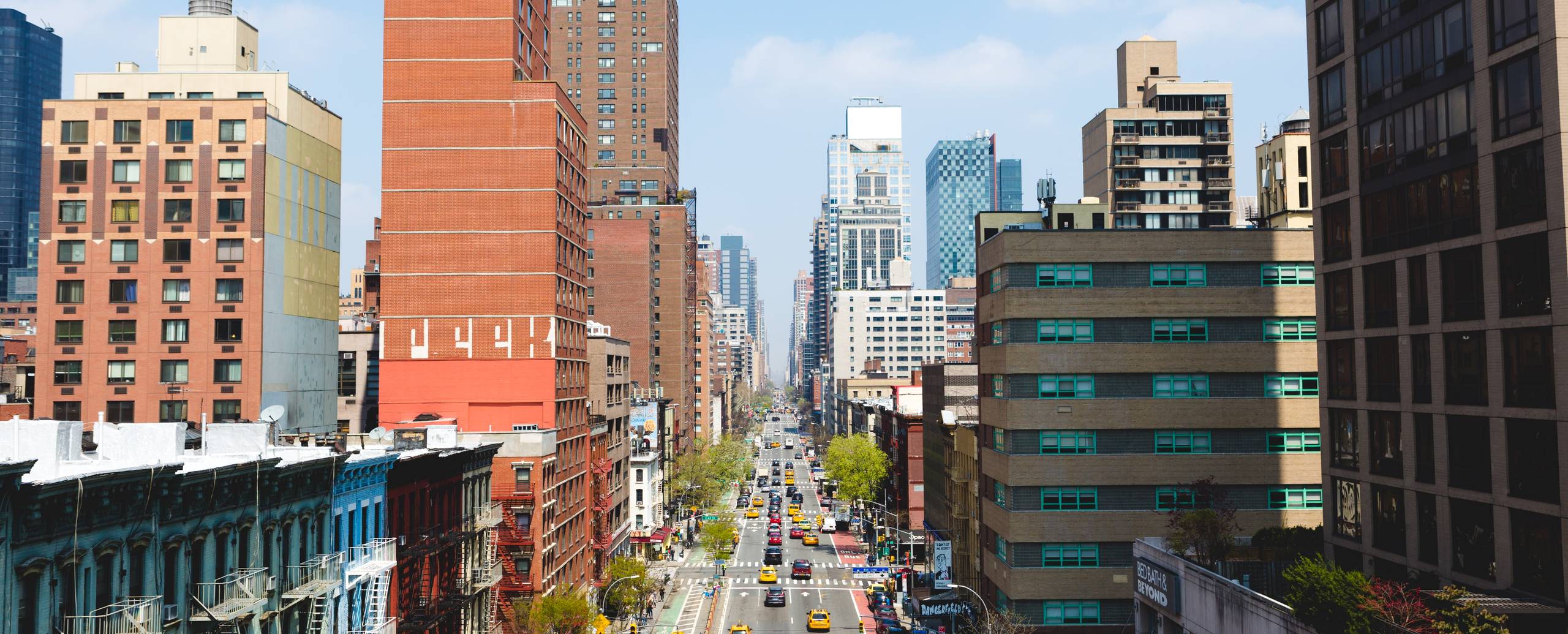 A Manhattan avenue seen between skyscrapers, yellow cabs on the street below