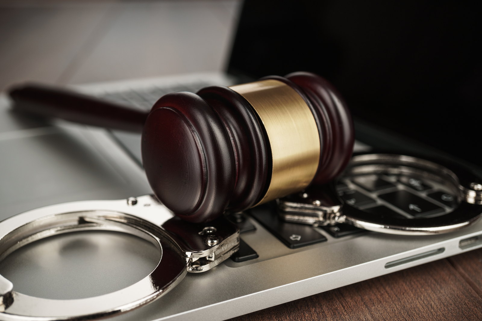 A gavel and handcuffs resting on a laptop — preserving evidence and preparing a Hudson County defense