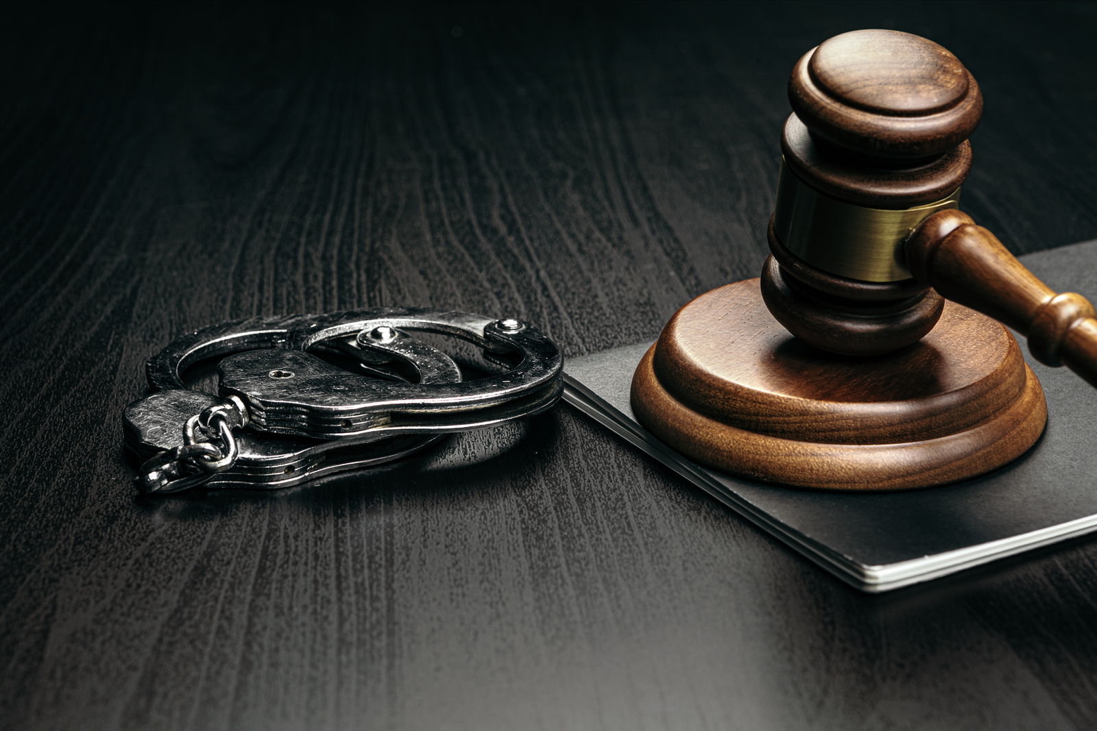 A gavel and a pair of handcuffs on a dark desk — what a Jersey City criminal charge puts at stake