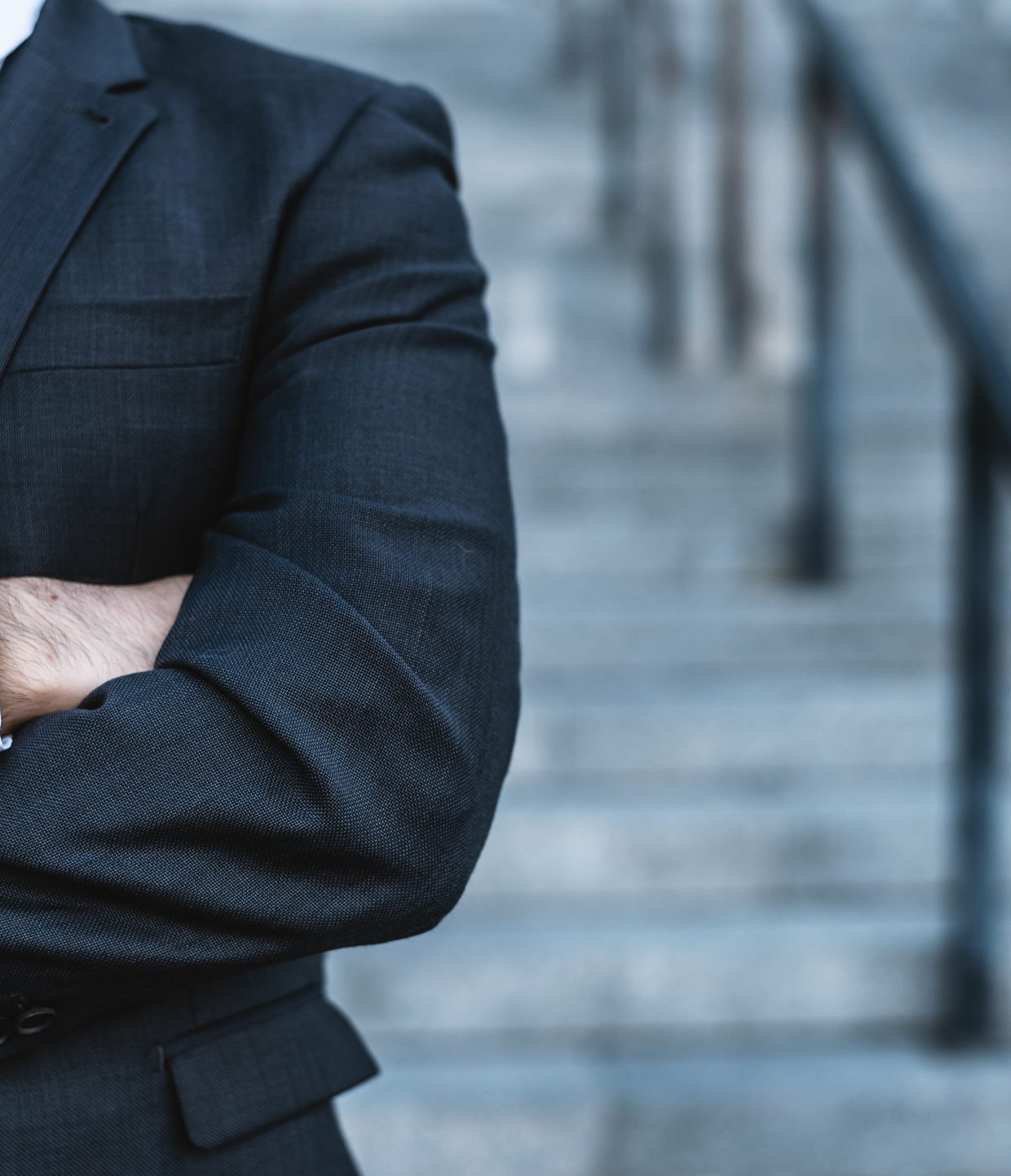 A lawyer in a dark suit standing with arms folded outside a courthouse &mdash; New York criminal defense