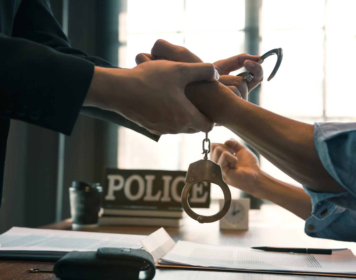 Handcuffs being fastened across a desk at a police station &mdash; facing criminal charges in Newark