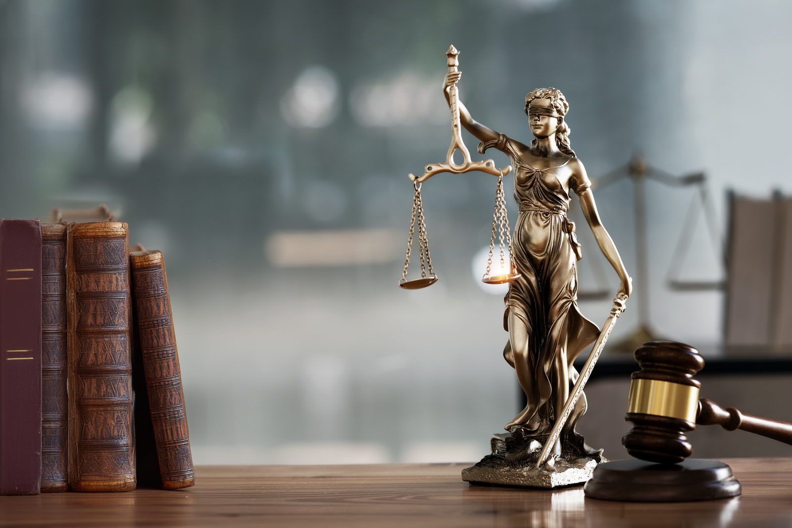 Statue of Lady Justice with scales beside law books and a gavel
