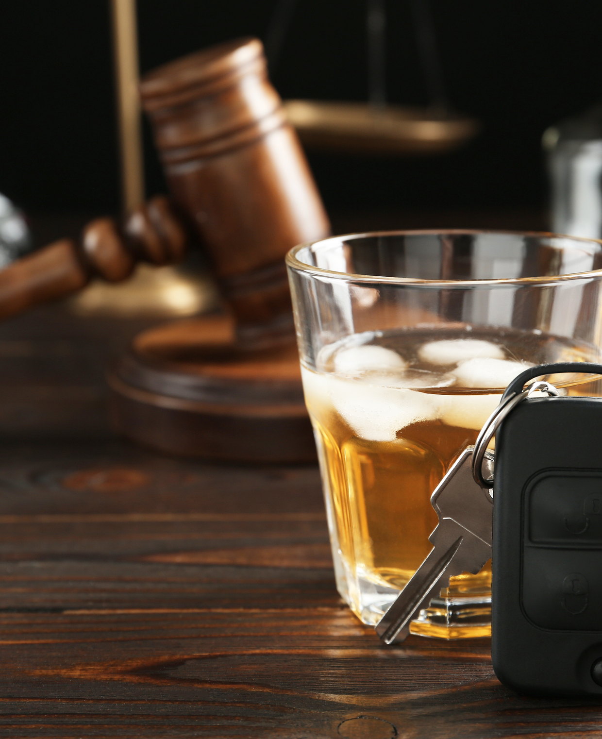 Car keys and a glass of alcohol beside a gavel