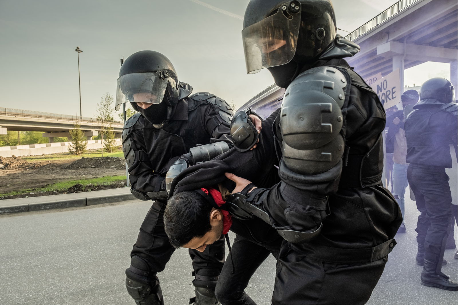 Two officers restraining a man while others stand by
