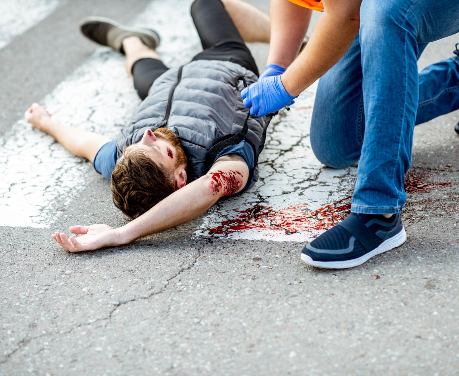 A responder giving first aid to an injured person in the road