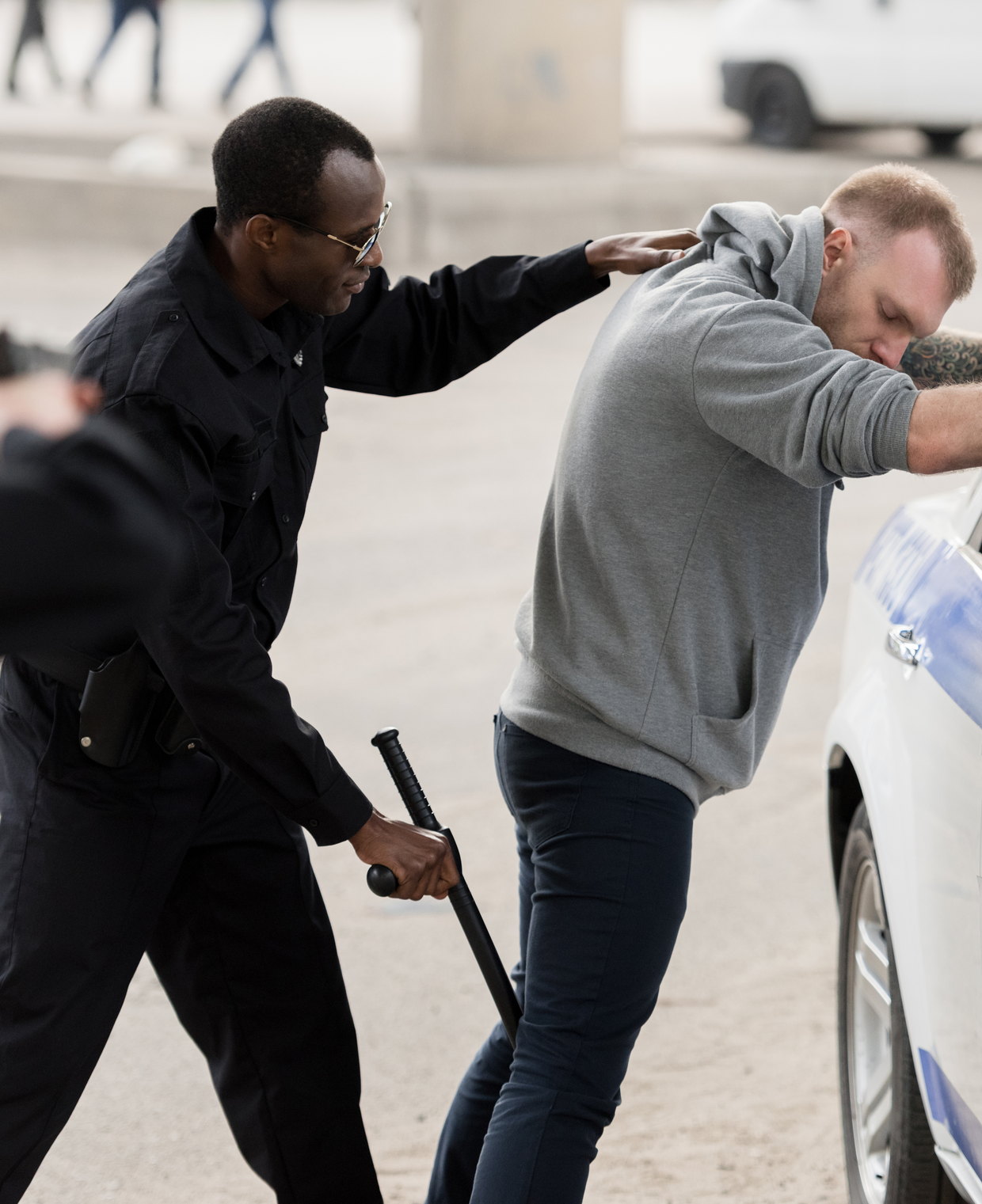 An officer with a baton beside a second officer making an arrest