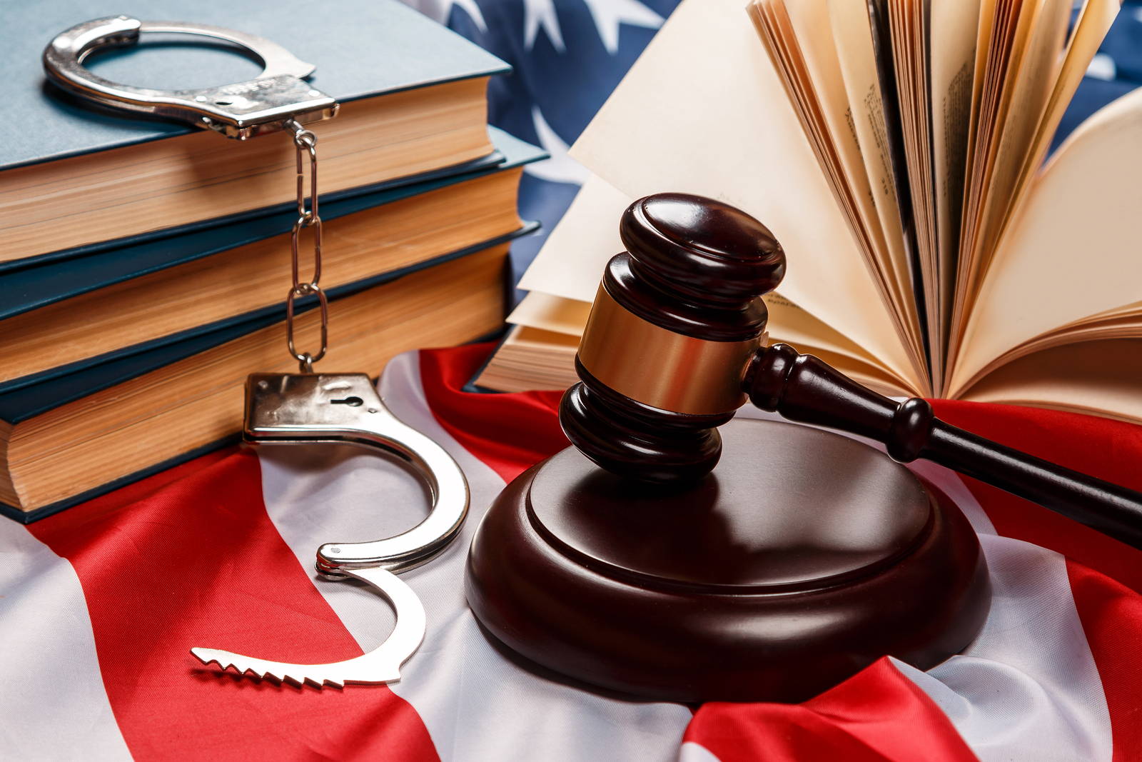 Gavel, law books and handcuffs resting on a United States flag