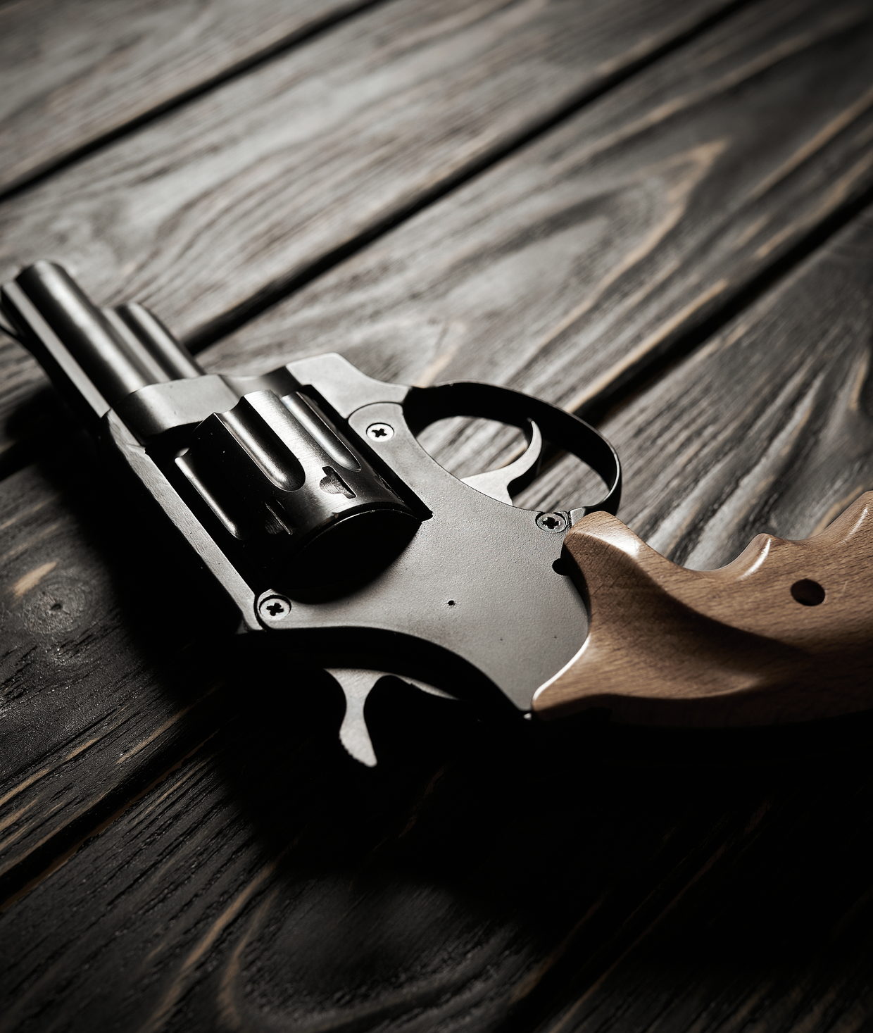 A revolver resting on a dark wooden surface
