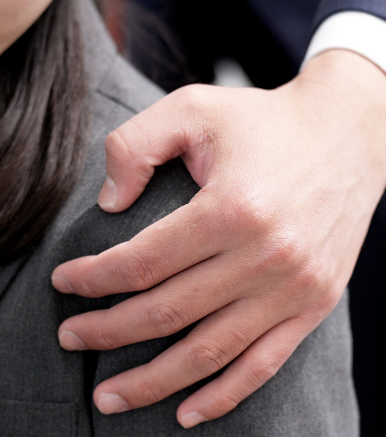 A hand placed on a person’s shoulder in a workplace