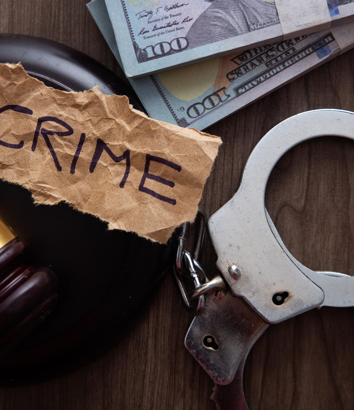 Handcuffs, a gavel and cash on a dark surface