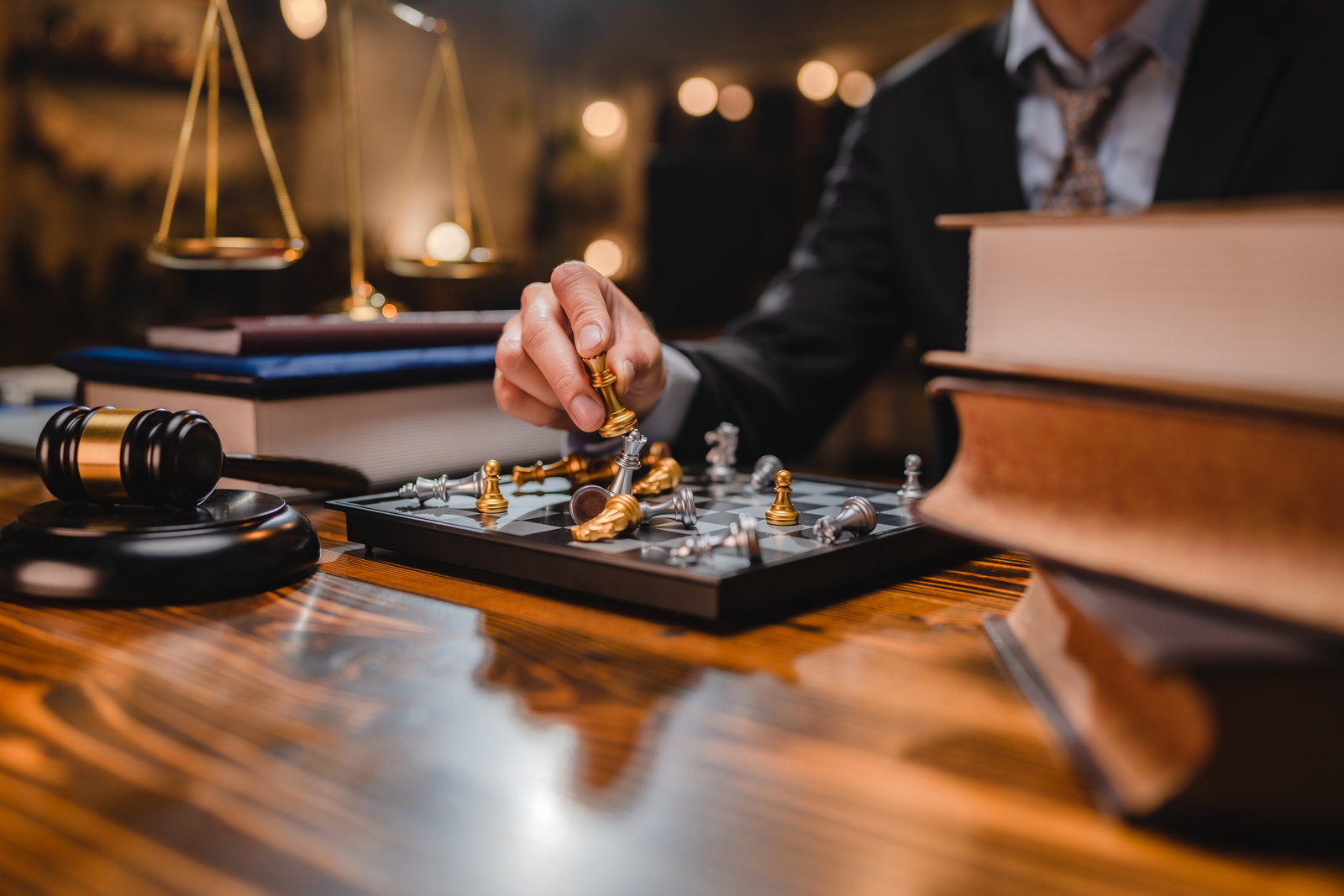 Chess pieces beside the scales of justice on a desk