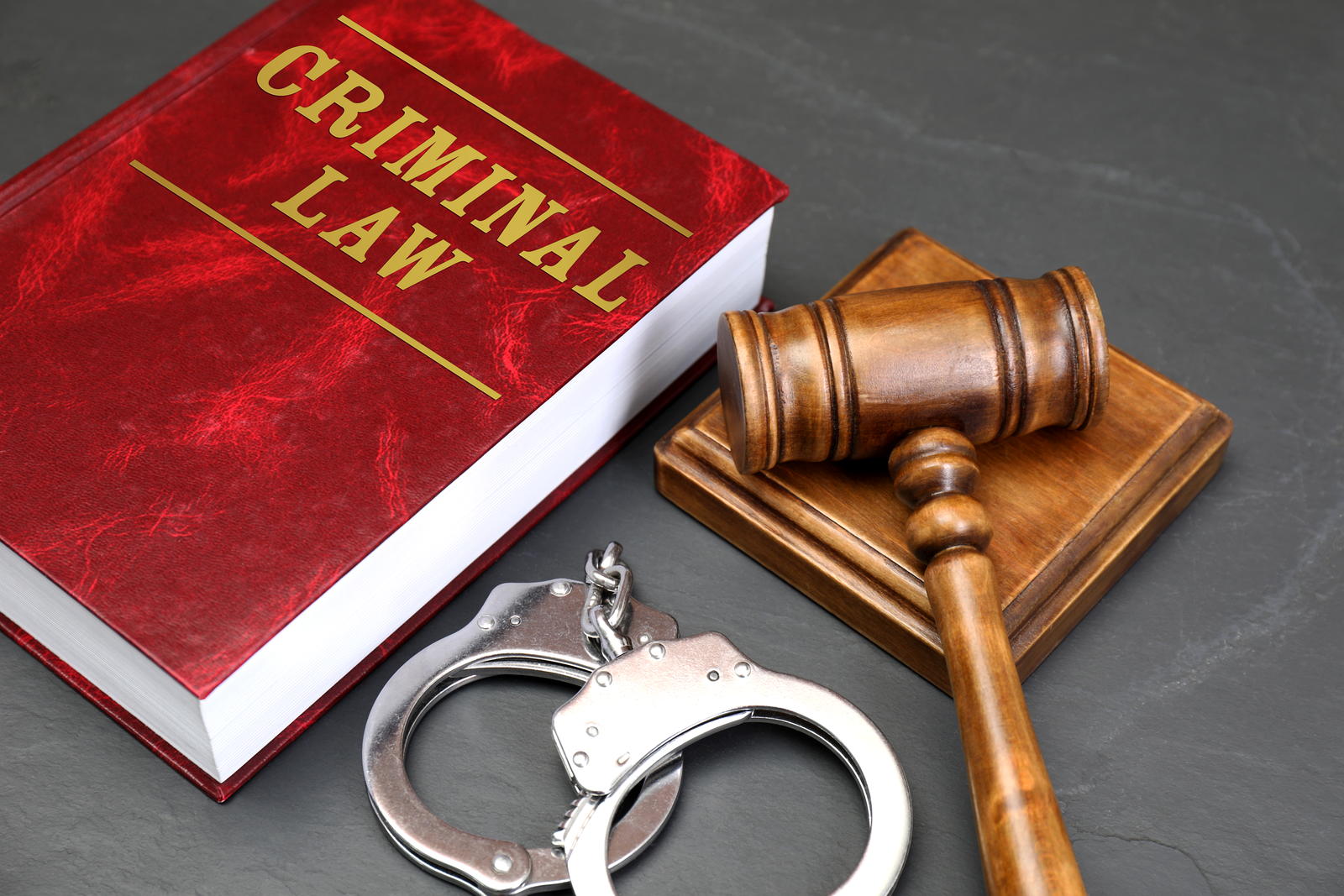 A criminal law volume with a gavel and handcuffs