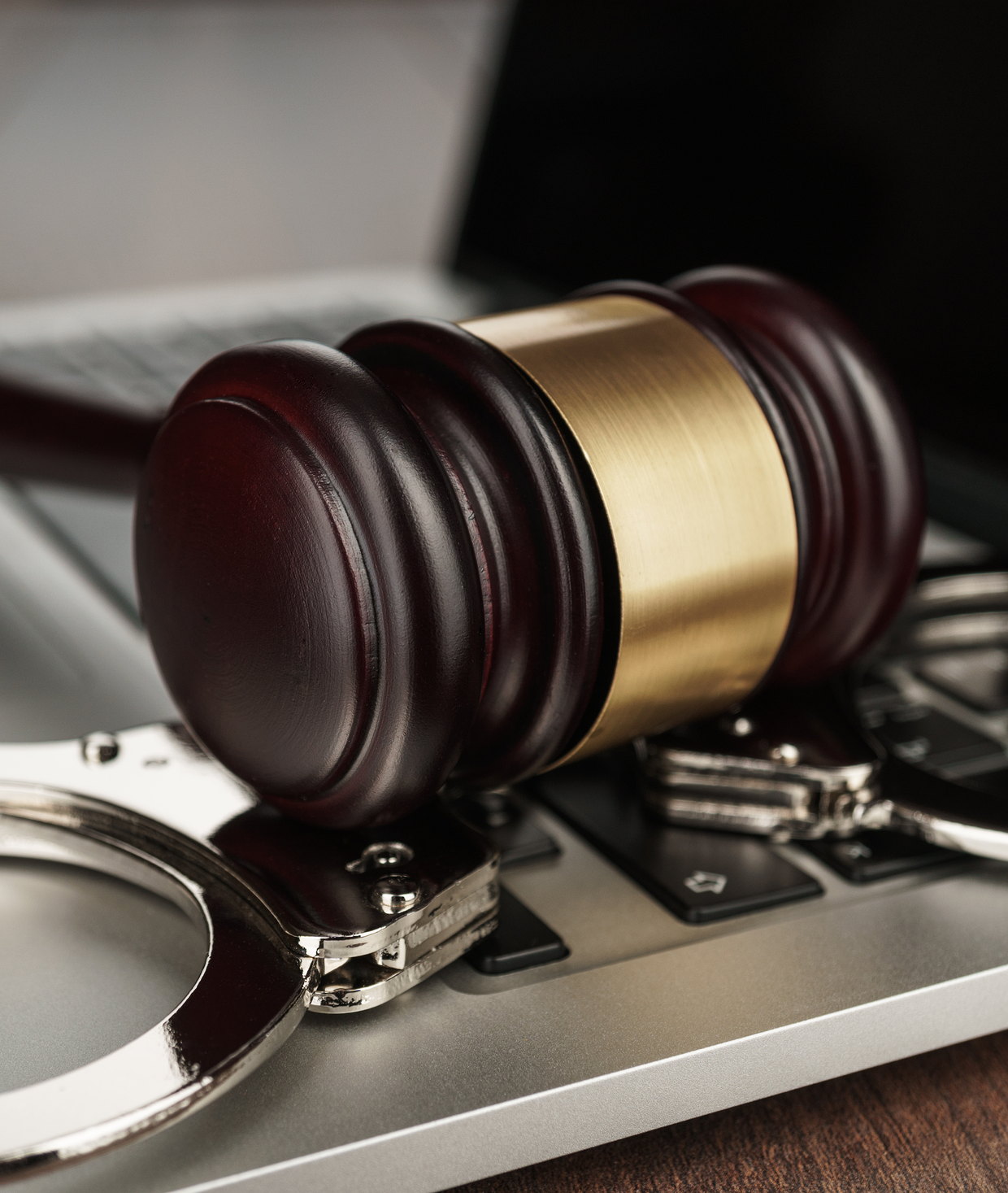 A gavel resting on handcuffs on a laptop