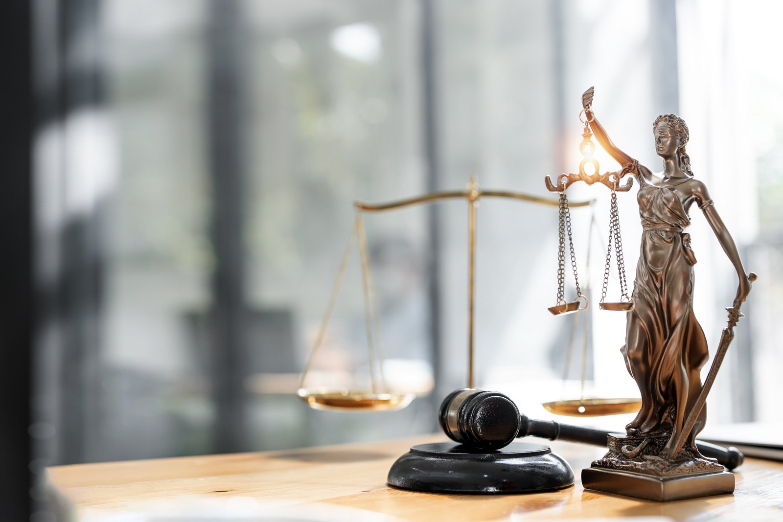 A statue of Lady Justice holding the scales beside a gavel