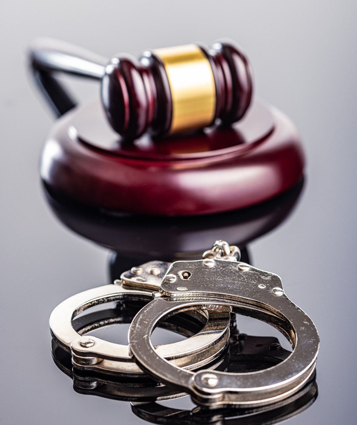 A gavel and handcuffs on a reflective surface