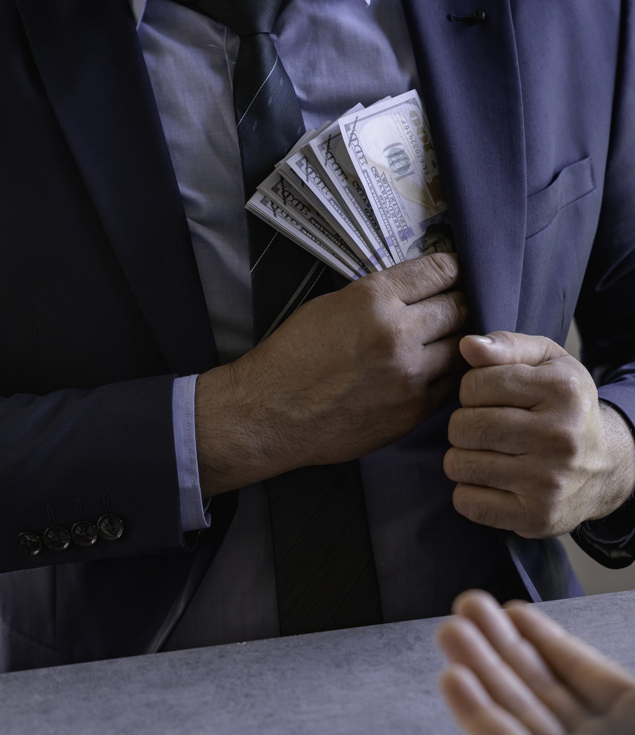 Banknotes being slipped into a suit jacket
